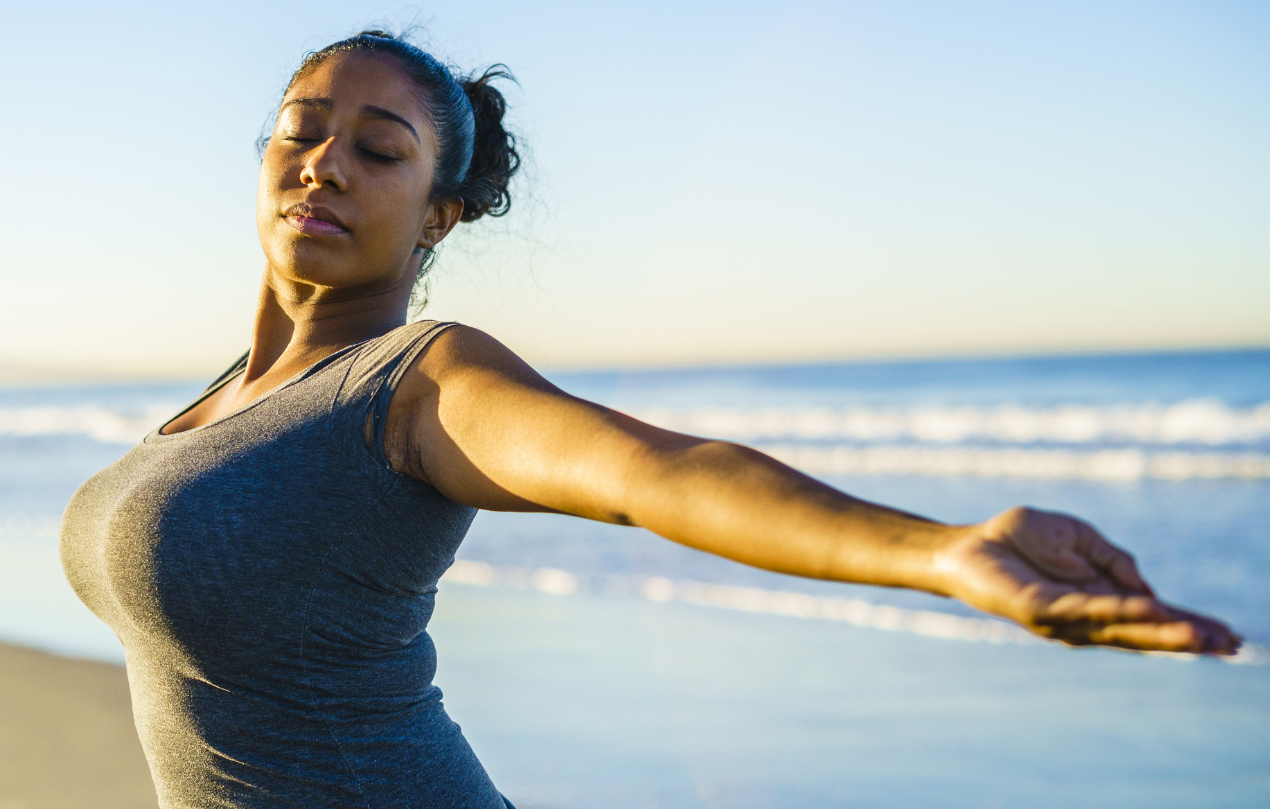 Young tanned mixed-race girl practicing fitness on the beach