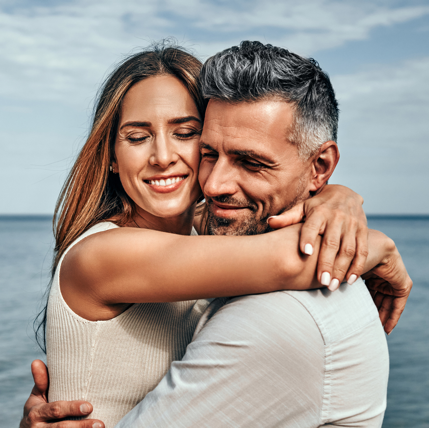 Close up view of a portrait of a handsome couple in love hugging while walking along the beach. Hormone Replacement Therapy in Greenville, SC