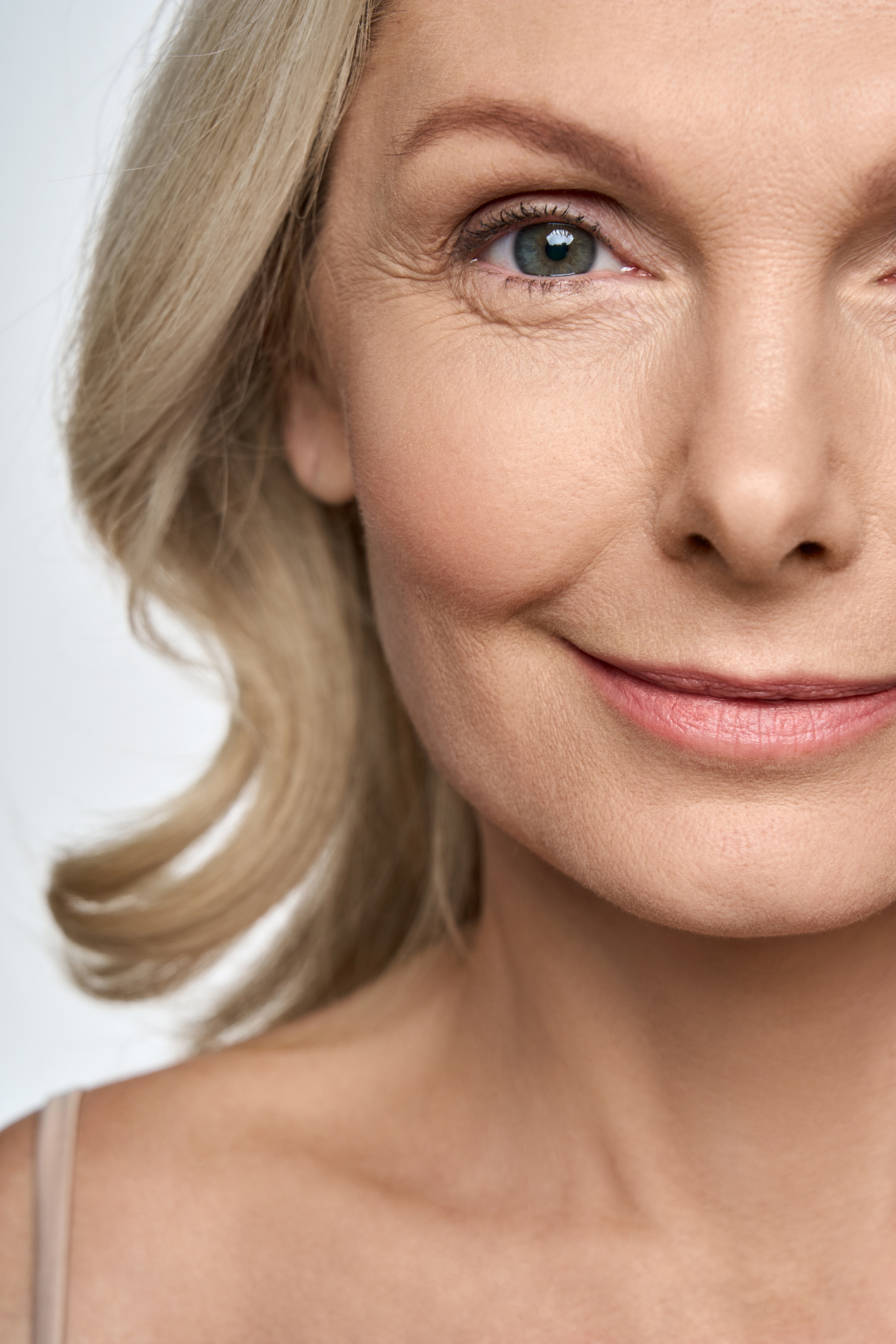 Face close up portrait of happy smiling mid age 50 years old woman isolated on white background. Advertising of facial skin care anti wrinkle tightening lift products for women in menopause. Blepharoplasty (Eyelid Surgery) in Greenville, SC